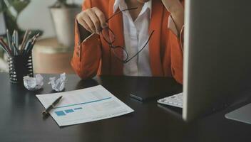 Asian Business woman using calculator and laptop for doing math finance on an office desk, tax, report, accounting, statistics, and analytical research concept photo