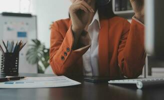 Asian Business woman using calculator and laptop for doing math finance on an office desk, tax, report, accounting, statistics, and analytical research concept photo