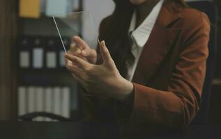 el retrato de una joven mujer asiática independiente está trabajando en su trabajo en una tableta de computadora en una oficina moderna. hacer un informe de análisis contable datos de inversión inmobiliaria, concepto de sistemas financieros y fiscales. foto