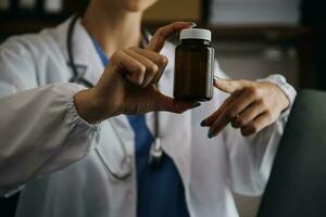 Young doctor with diary sitting at desk in medical clinic photo