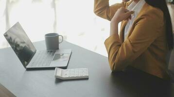 el retrato de una joven mujer asiática independiente está trabajando en su trabajo en una tableta de computadora en una oficina moderna. hacer un informe de análisis contable datos de inversión inmobiliaria, concepto de sistemas financieros y fiscales. foto