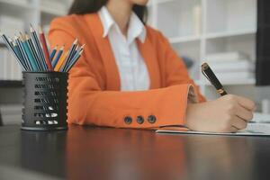 el retrato de una joven mujer asiática independiente está trabajando en su trabajo en una tableta de computadora en una oficina moderna. hacer un informe de análisis contable datos de inversión inmobiliaria, concepto de sistemas financieros y fiscales. foto