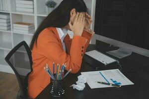 Asian women are stressed while working on laptop, Tired asian businesswoman with headache at office, feeling sick at work, copy space photo