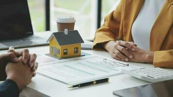 Real estate broker agent presenting and consult to customer to decision making sign insurance form agreement, buy and sell home model, concerning mortgage loan offer for and house insurance video