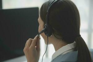 Beautiful female call center operator working on computer in office photo