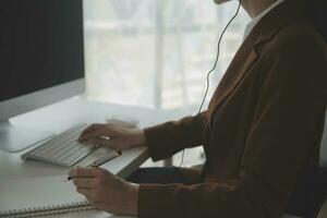 Beautiful female call center operator working on computer in office photo