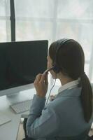 Beautiful female call center operator working on computer in office photo