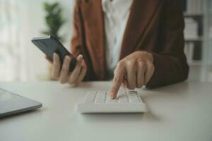 cierre a una mujer de negocios usando una calculadora y una computadora portátil para hacer finanzas matemáticas en un escritorio de madera, impuestos, contabilidad, estadísticas y concepto de investigación analítica foto