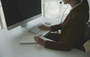 Beautiful female call center operator working on computer in office photo