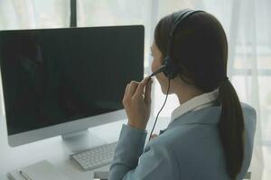 Beautiful female call center operator working on computer in office photo