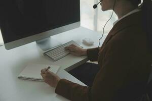 Beautiful female call center operator working on computer in office photo