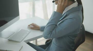 Beautiful female call center operator working on computer in office photo