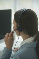 Beautiful female call center operator working on computer in office photo