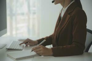 Beautiful female call center operator working on computer in office photo