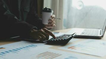 Close up businessman hand using calculator and working with laptop calculate about finance accounting at coffeeshop outdor.finance accounting concept photo