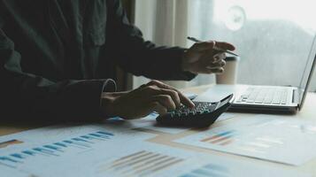 Close up businessman hand using calculator and working with laptop calculate about finance accounting at coffeeshop outdor.finance accounting concept photo