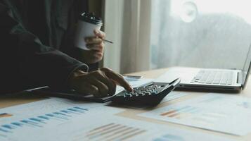 Close up businessman hand using calculator and working with laptop calculate about finance accounting at coffeeshop outdor.finance accounting concept photo