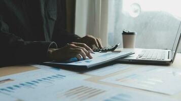 Close up businessman hand using calculator and working with laptop calculate about finance accounting at coffeeshop outdor.finance accounting concept photo
