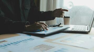 Close up businessman hand using calculator and working with laptop calculate about finance accounting at coffeeshop outdor.finance accounting concept photo