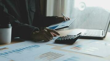 Close up businessman hand using calculator and working with laptop calculate about finance accounting at coffeeshop outdor.finance accounting concept photo