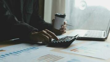 Close up businessman hand using calculator and working with laptop calculate about finance accounting at coffeeshop outdor.finance accounting concept photo