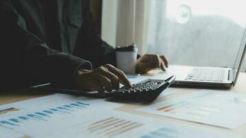 Close up businessman hand using calculator and working with laptop calculate about finance accounting at coffeeshop outdor.finance accounting concept photo