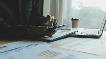 Close up businessman hand using calculator and working with laptop calculate about finance accounting at coffeeshop outdor.finance accounting concept photo