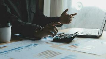 Close up businessman hand using calculator and working with laptop calculate about finance accounting at coffeeshop outdor.finance accounting concept photo