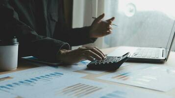 Close up businessman hand using calculator and working with laptop calculate about finance accounting at coffeeshop outdor.finance accounting concept photo
