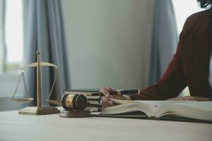 Justice and law concept.Male judge in a courtroom with the gavel, working with, computer and docking keyboard, eyeglasses, on table in morning light photo