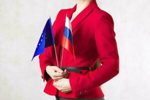 A young woman between 30 and 40 years old hold two flags of EU and Russia. photo