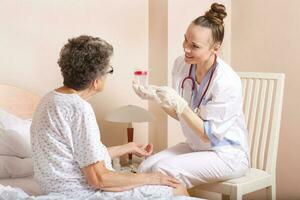 Geriatrician visits a senior woman, Medical sister gives a collection cup to old woman photo