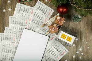 Blank sheet of paper and small paper house with coins on the New Year's background. photo