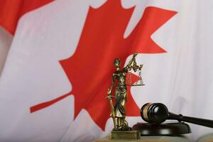 Statue of Themis and judge's gavel on a book. Flag of Canada in the background. photo