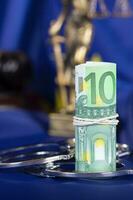 Pile of 100 euros surrounded by handcuffs on a flag of EU. photo