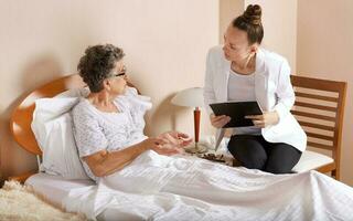 Visit of senior social work assistant to an old woman photo