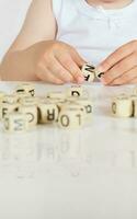 Small girl composes words from letters. Closeup photo