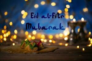 Congratulation Eid al-Fitr Mubarak Arabic sweets on a wooden surface. photo