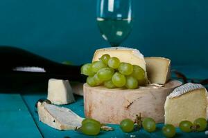 Cheese, grapes and wine on wooden cyan surface. photo