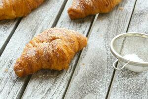 French croissant on a gray wooden surface. Closeup photo