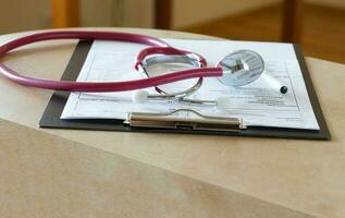 Stethoscope on a results of blood analysis in French a doctors table. Closeup photo