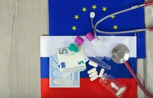 Medication,test tubes,money and stethoscope on European and Russian flags photo