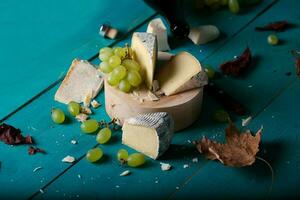 Cheese, grapes and wine on wooden cyan surface. photo
