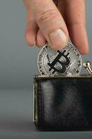 persona pone bitcoin en un negro billetera. foto