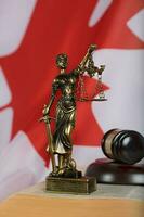 Statue of Themis and judge's gavel on a book. Flag of Canada in the background. photo