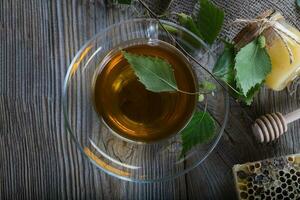 Birch leaf train a glass cup on a wooden surface. photo