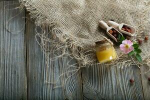 Wild rose hip honey in a glass bottle on a wooden surface. photo