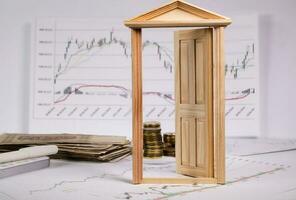 Coins on a stock market charts behind opened small wooden door. photo