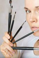 Make up brushes kit close to her face of a young lady. Closeup photo