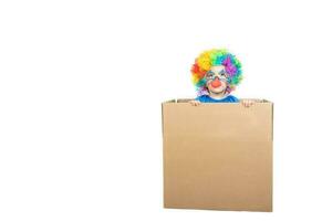 Boy of five years dressed in the costume of a clown stays in a carton paper box. photo